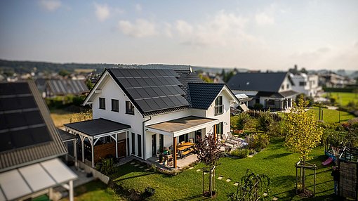 Modernes Einfamilienhaus mit Garten und vollflächiger Photovoltaik-Anlage auf dem Dach.