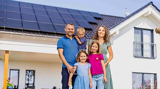 Familie vor Haus mit Solarmodulen