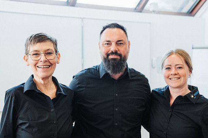 Drei Mitarbeitende von enatek lächeln freundlich