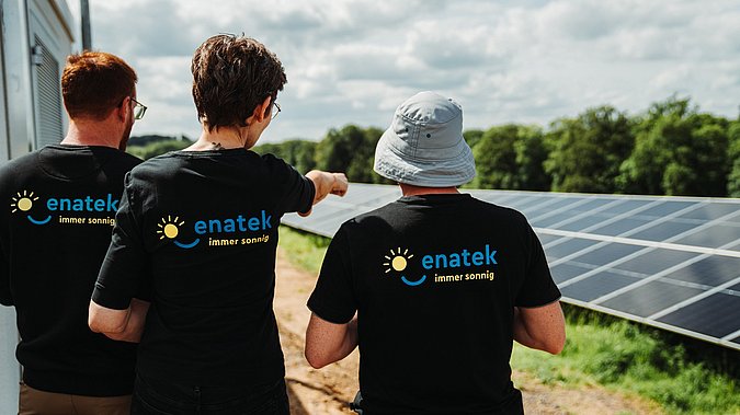 Mitarbeiter von enatek zeigen auf PV-Anlage