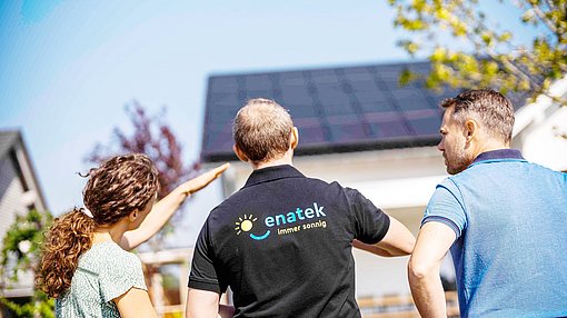 Eine Ehepaar und ein ENATEK Mitarbeiter stehen vor einem Eigenheim mit einer Photovoltaikanlage